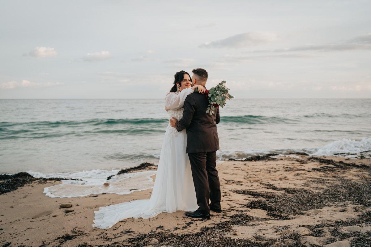 sposi durante un momento spontaneo del matrimonio in spiaggia a Pula